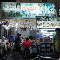 ベトナムの屋台村で食事を楽しむ地元の人々と活気ある調理風景の写真