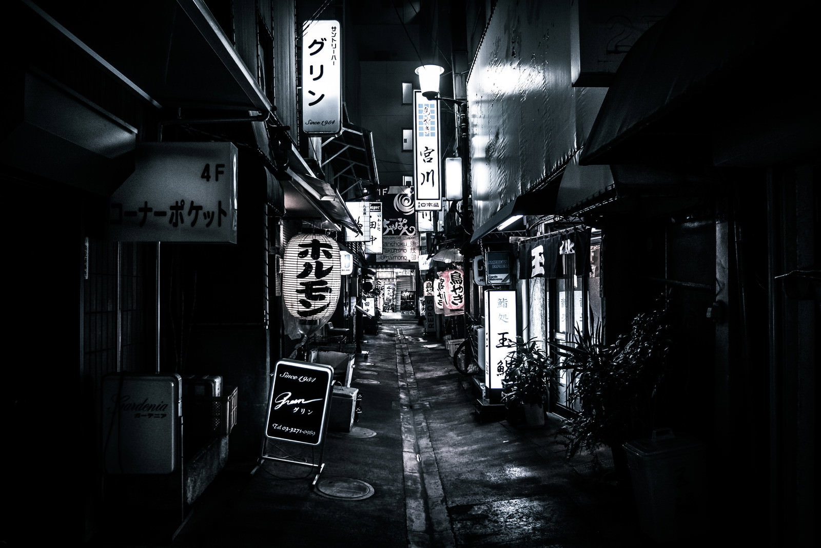 細い路地裏に居酒屋やスナックの看板と提灯が並ぶ夜の街並み