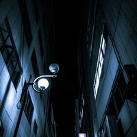 夜間のビルとビルの隙間に灯る街灯と都市景観の写真