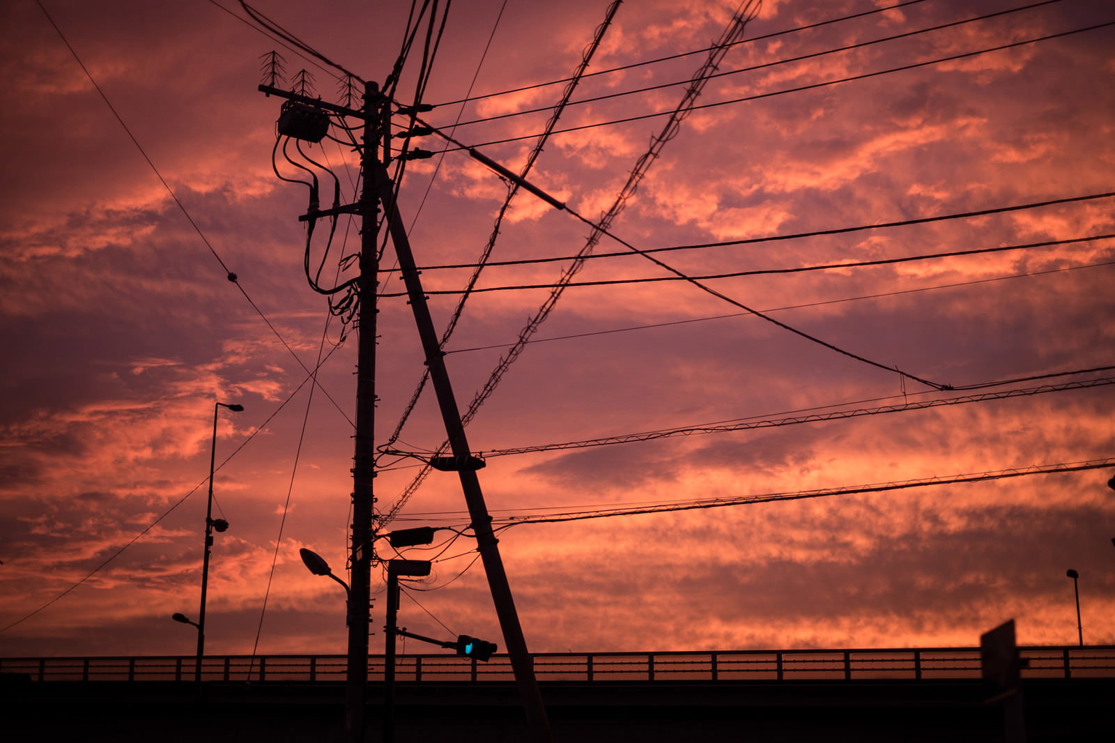 夕焼けの空に浮かぶ電柱と電線のシルエット