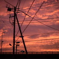 夕焼け空を背景にした電柱と電線のシルエットの写真