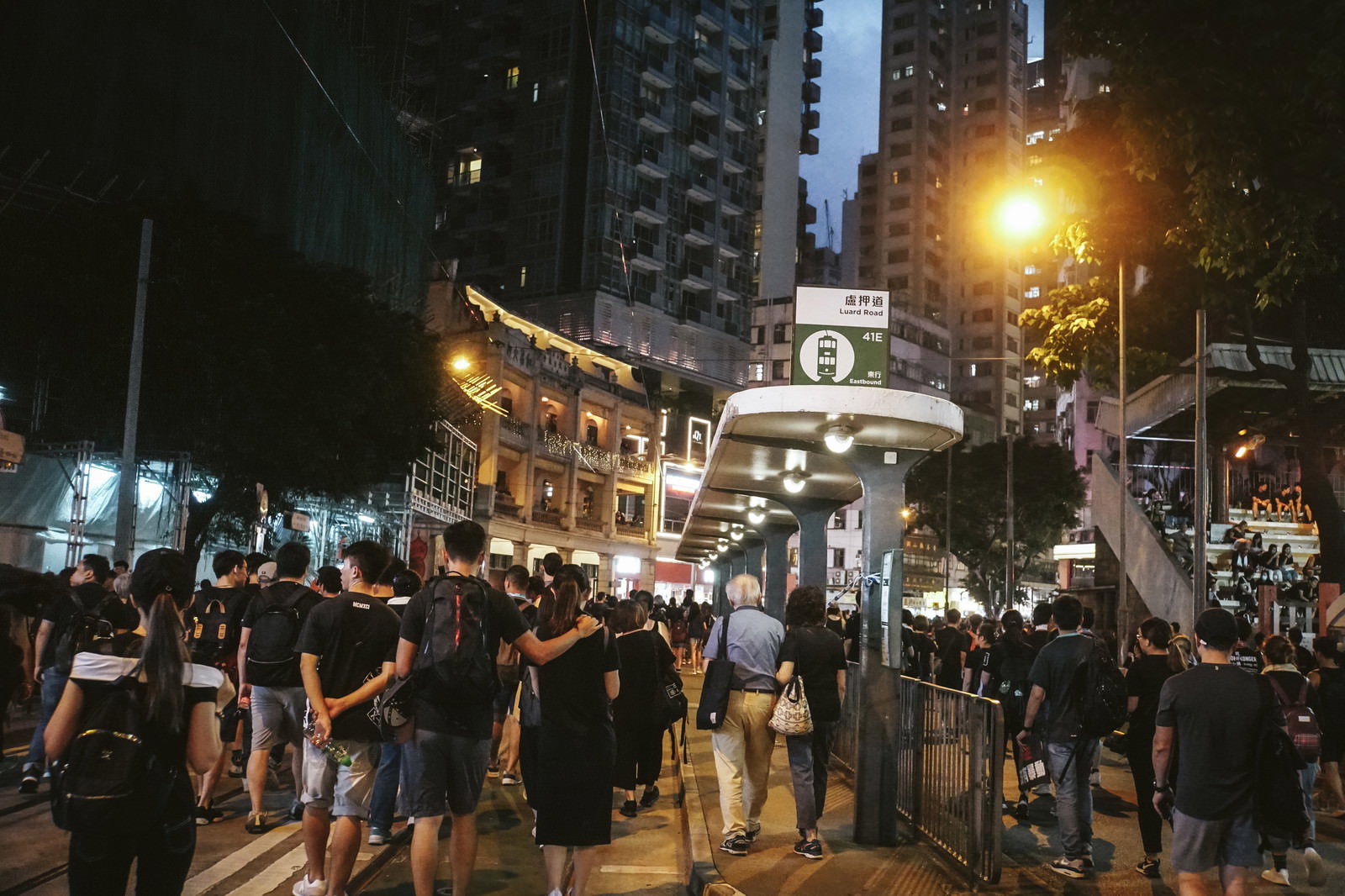 香港の夜間路上で黒装束の群衆がデモ行進で歩いている