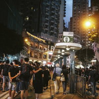 香港の夜間路上で黒装束の群衆が歩くデモ行進の写真