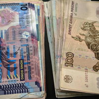 机の上に重ねて置かれたルーブルと香港ドルの紙幣の写真