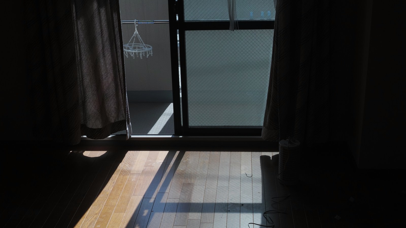 ワンルームの部屋で窓から陽光が差し込み、床に影が落ちている