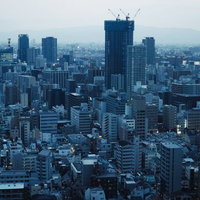 夕暮れの都心ビル群と建設中の高層ビル群の都市風景の写真