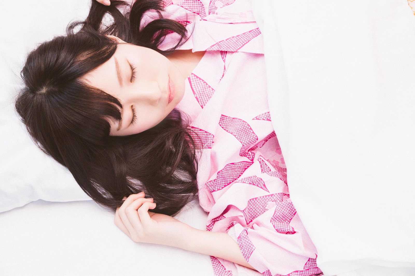 ピンク色の寝具に包まれて穏やかに眠る女性の横顔［モデル：モデルリリース］