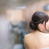 伊東温泉旅館の露天風呂で湯けむりに包まれる女性の後ろ姿の写真