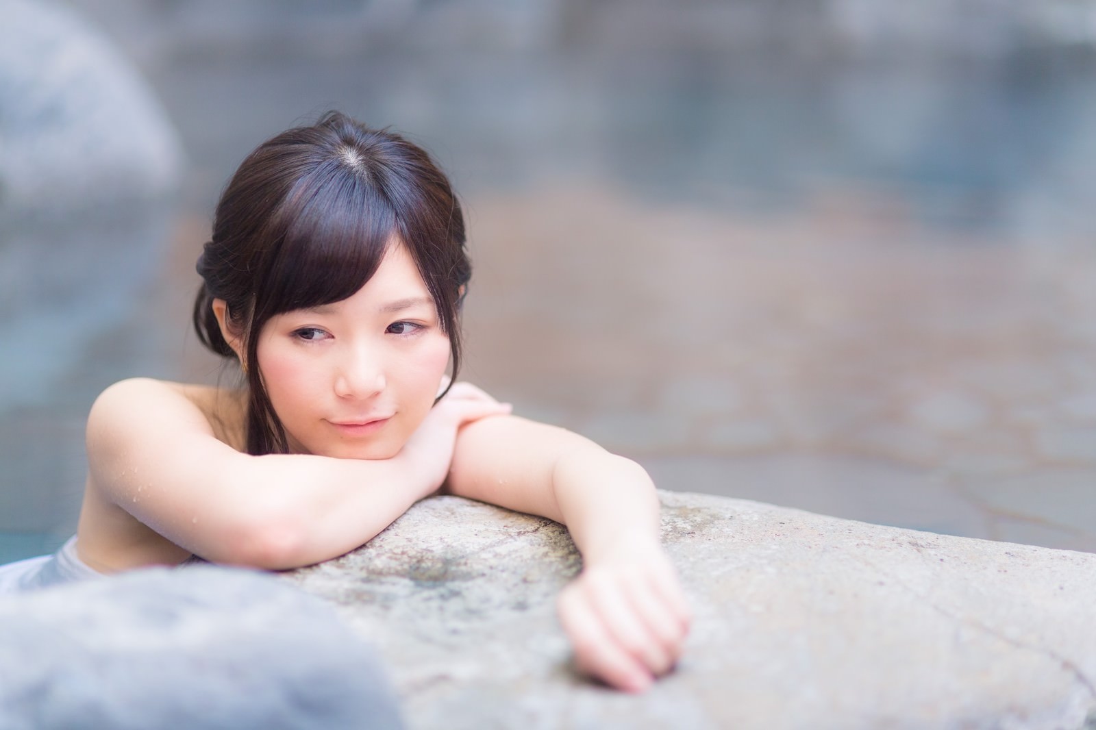 温泉の湯船から上半身を出し、のぼせた表情の女性［モデル：モデルリリース］