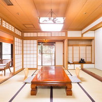 赤茶色のテーブルと紫縁の畳に障子や格子窓がある旅館の和室の写真