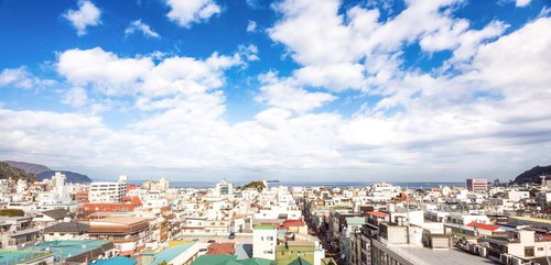 青空に白い雲が広がる海沿いの伊東の街並みと建物群の遠景