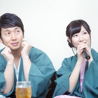 伊東温泉旅館のカラオケで熱唱する彼女を見守る彼氏の写真