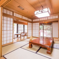 紫縁の畳に赤茶色の座卓と奥に小机と椅子がある旅館の和室客室の写真