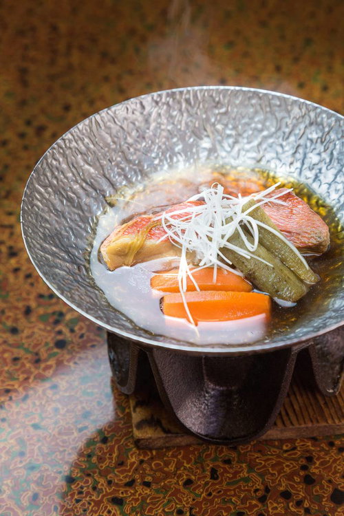 銀色の模様の器に魚の切り身と人参と大根が盛られたキンメダイの煮付け