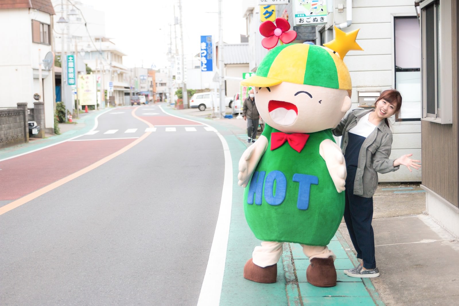 大原中央商店街のHOTくんと笑顔で並ぶ女性［モデル：ホットくん 河村友歌］