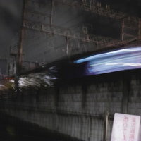 夜間に高速で通り過ぎる列車と跨線橋の不気味な風景の写真