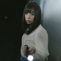 ハンドライトを片手に暗闇を探索する女性の姿の写真