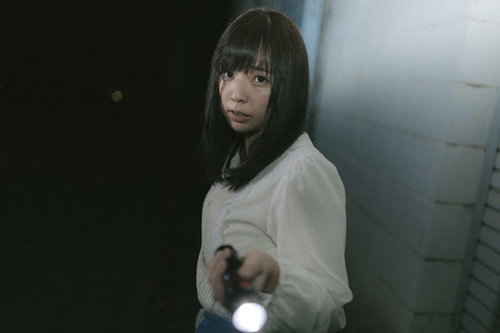 ハンドライトを片手に暗闇を探索する女性の姿