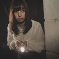 深夜にひとりで懐中電灯を持ち廃墟を探索する女性の写真