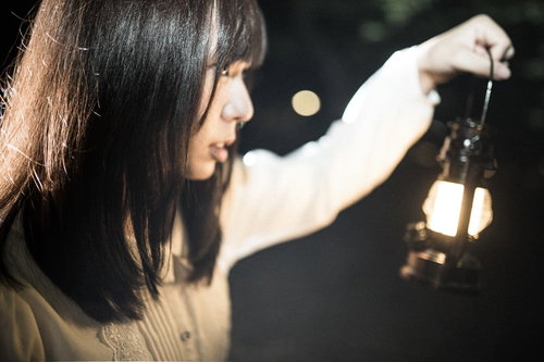 ランタンを持って暗闇で逃亡者を探す女性の不気味な姿