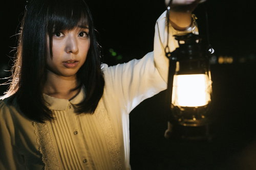ランタンを片手に暗闇を歩く不安そうな表情の女性