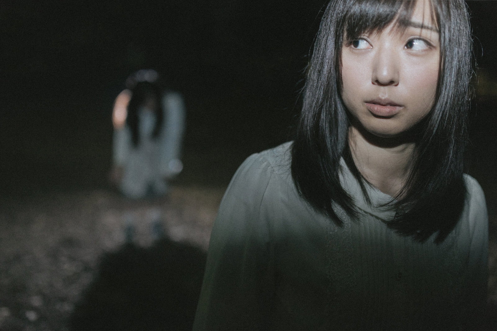 暗闇の中で恐怖に震える女性と背後に見える不気味な影［モデル：さとうゆい 河村友歌］