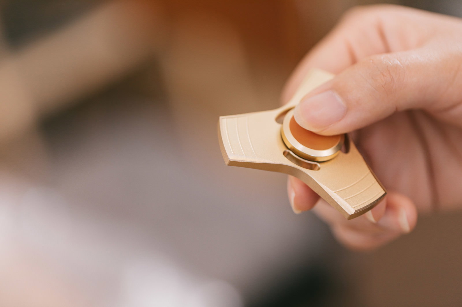 金色のハンドスピナーを指で持つ手のクローズアップ