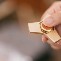 ストレス発散に最適な金色のハンドスピナーを指で持つ手の写真