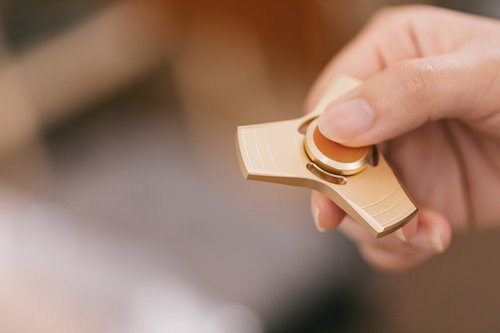 ストレス発散に最適な金色のハンドスピナーを指で持つ手