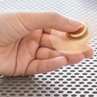 金色のハンドスピナーが手のひらでシュルシュル回るの写真