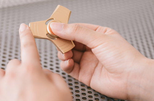 高速回転するハンドスピナーを指で回す手元