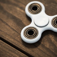 木目調テーブルに置かれた白いハンドスピナーの写真