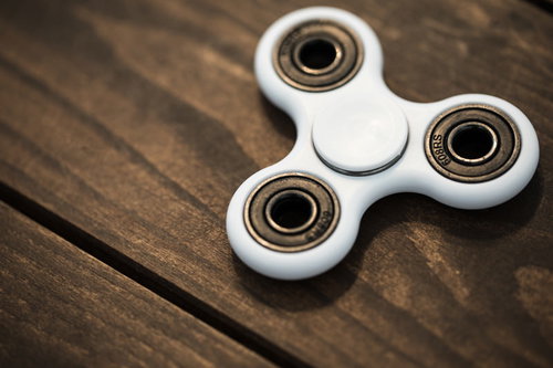 木目調テーブルに置かれた白いハンドスピナー