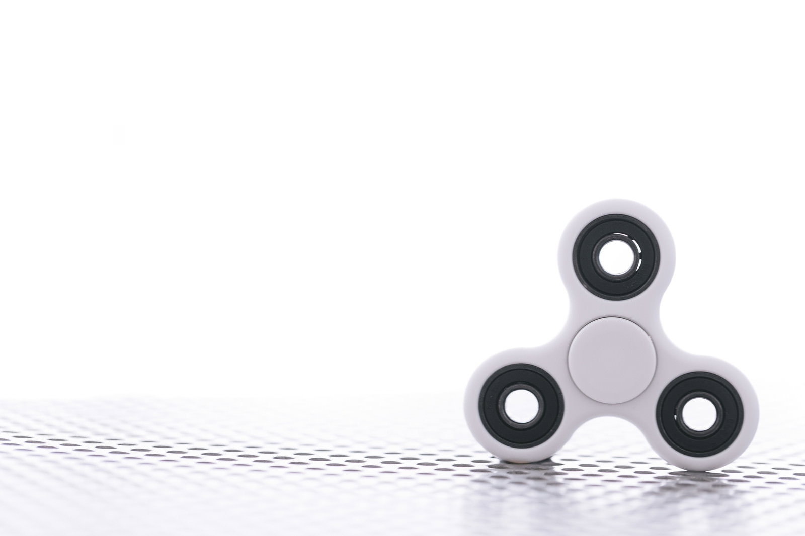 白い背景に置かれた3つ穴のハンドスピナー、ベアリング内蔵