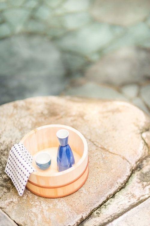 石畳の上に木の桶に入った青い瓶と小さな器と水玉模様の布