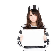 白いホワイトボードを掲げる無実の罪を訴える美人囚人の写真