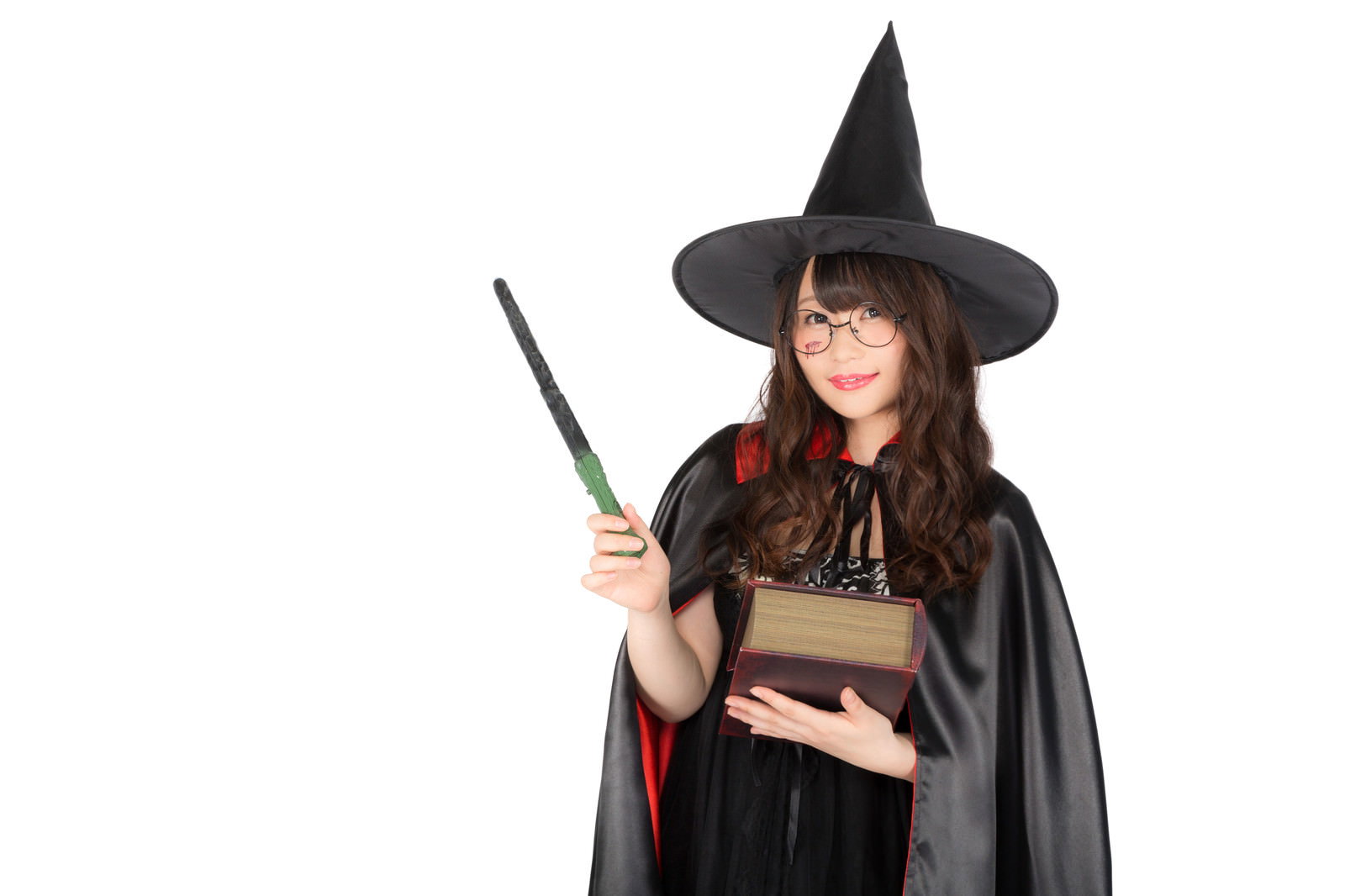 黒い魔法使い帽と黒マントを着た女性が杖と本を持つ［モデル：茜さや］
