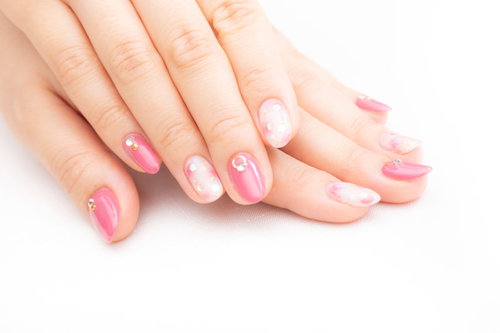 ピンク色のネイルアートが施された手と指先