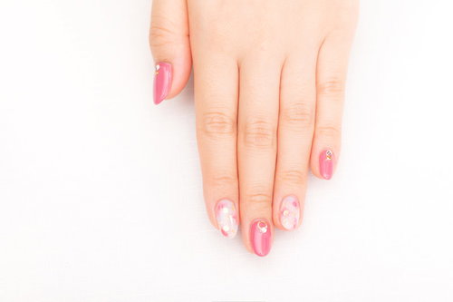 ピンク色のネイルアートを施した女性の手先
