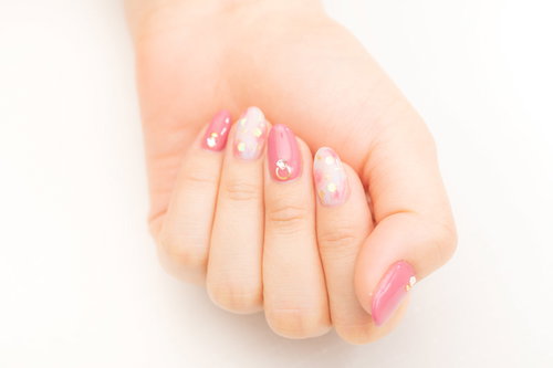 ピンクのネイルデザインを施した女性の指先