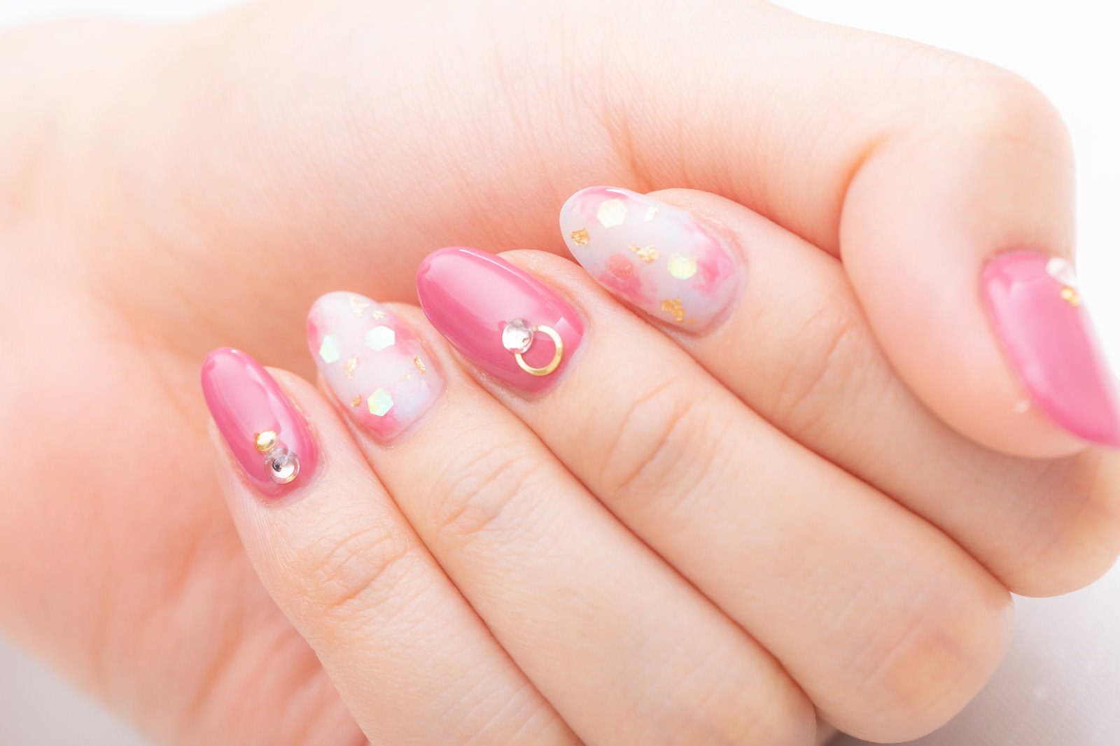 ピンクとホワイトのネイルアートを施した女性の手