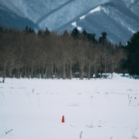 福島県郡山市の雪原に立つ赤いカラーコーンの写真