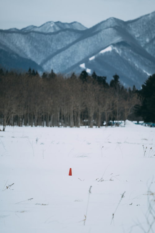 福島県郡山市の雪原に立つ赤いカラーコーン
