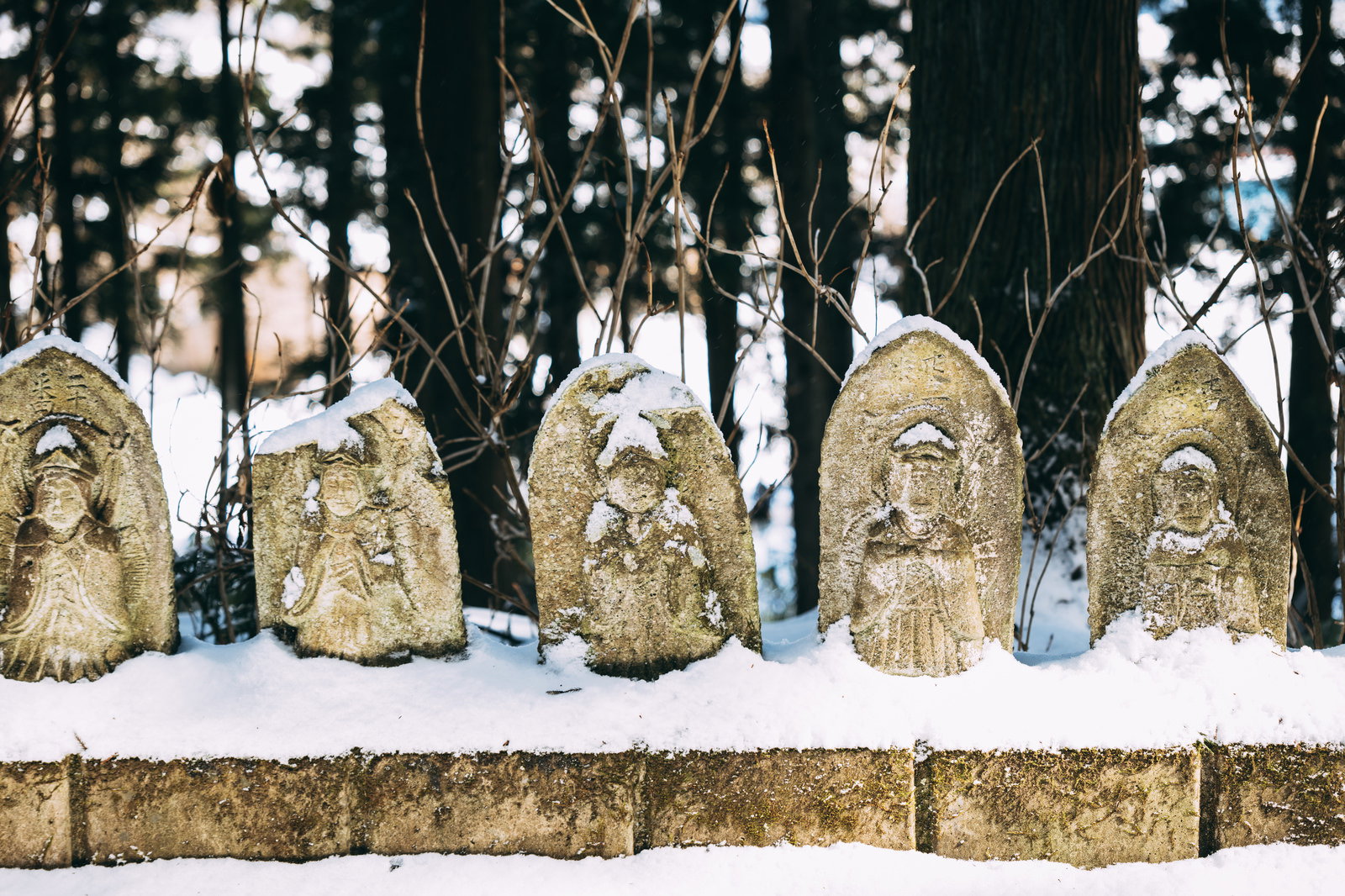 雪をかぶった複数のお地蔵さんが一列に並ぶ冬景色