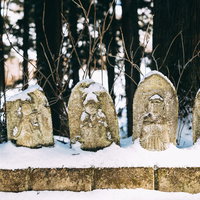 雪をかぶる一列のお地蔵さんの写真