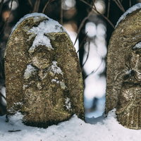 雪をかぶる石造りのお地蔵様の写真