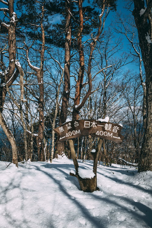 日本一遊歩道の雪道に立つ木製道標と冬の風景