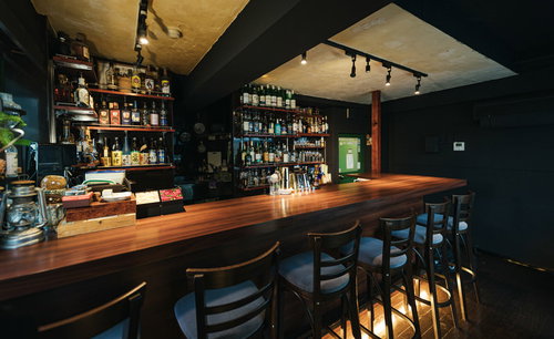 落ち着いた照明の木製カウンターバーの店内