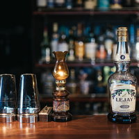 ルジェクレームドカシスのくびれたボトルをバーカウンターに配置の写真