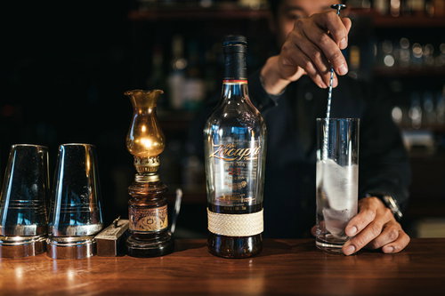 ロンサカパのソーダ割りのビルド、 バースプーンを使ってグラスを冷やすバーテンダー